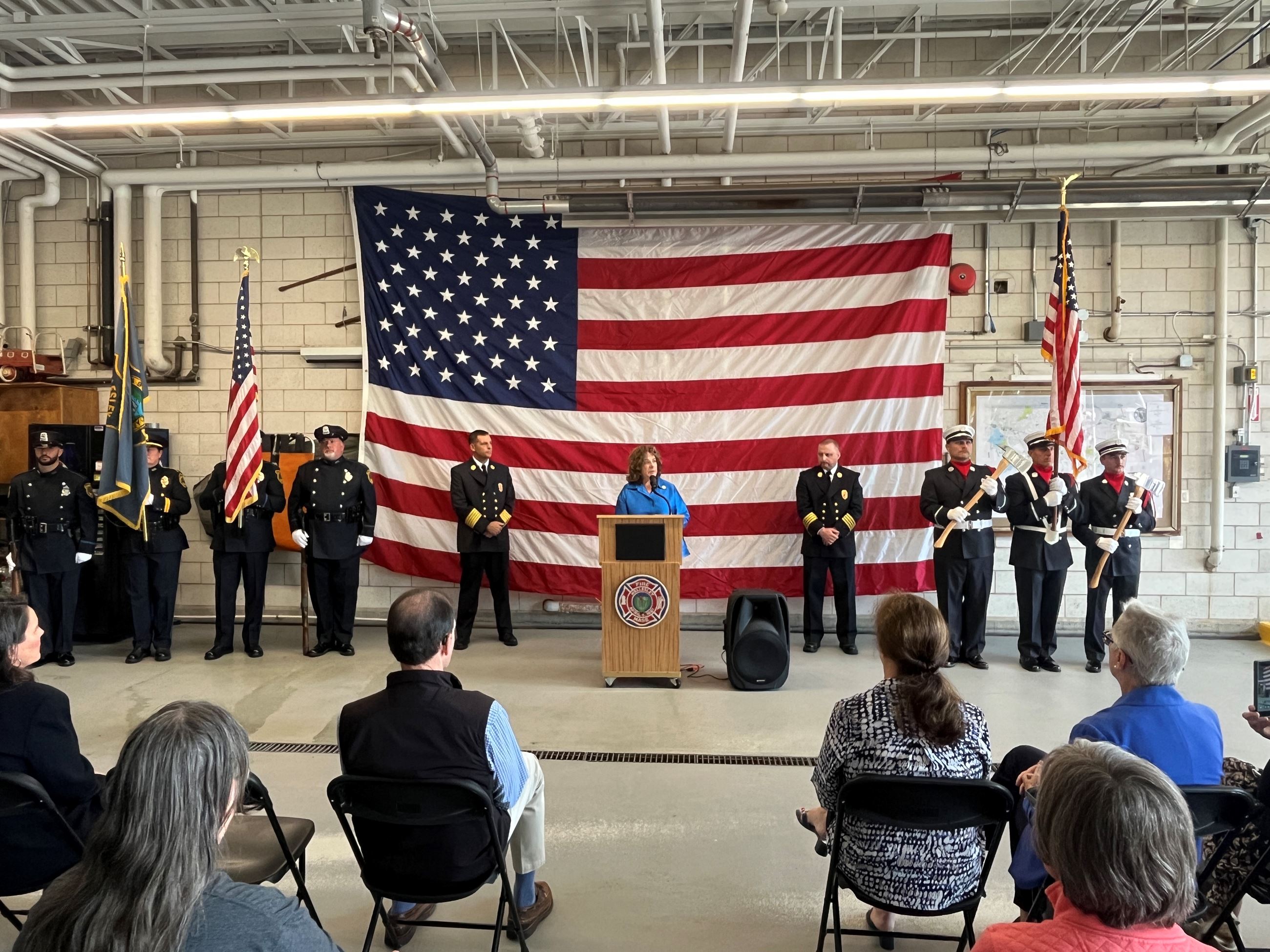 Select Board chair Marjorie Freiman speaking at 9/11 ceremony in front of the American flag